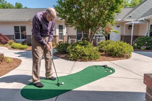Resident playing golf on an outdoor putting green