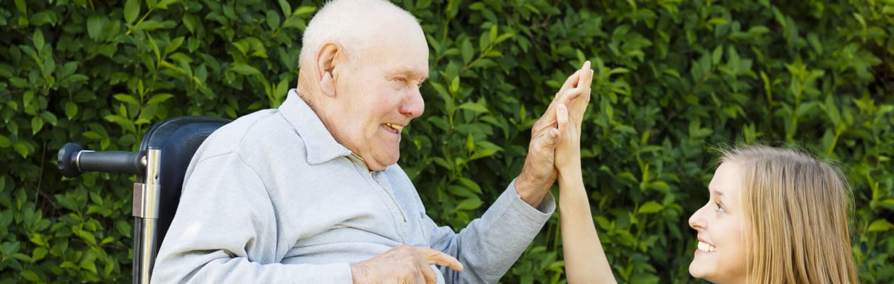 A senior man and caregiver sharing a joyful moment outdoors