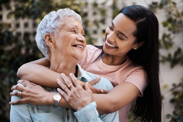 A caregiver hugging a senior resident with smiles