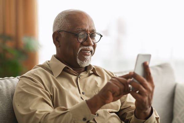 Senior man using a smartphone in a cozy setting