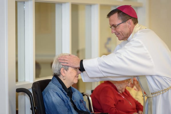 A resident receiving a blessing from a clergyman