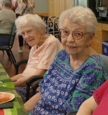 Two elderly women smiling at a dining table