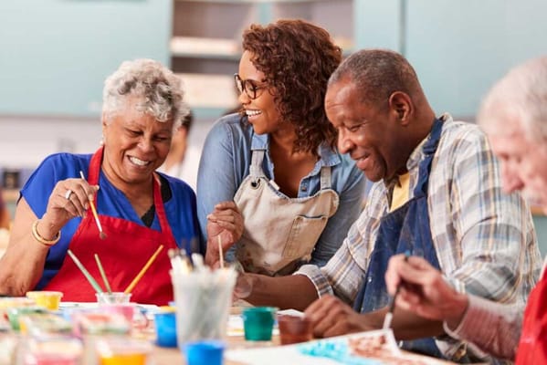 Residents engaged in a painting activity with staff