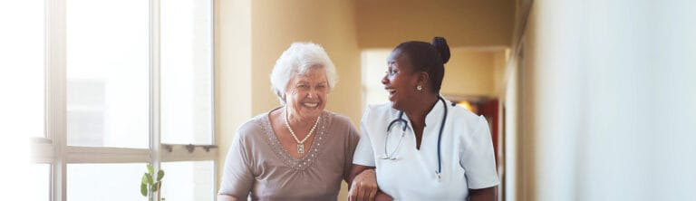 A caregiver and resident laughing in a hallway
