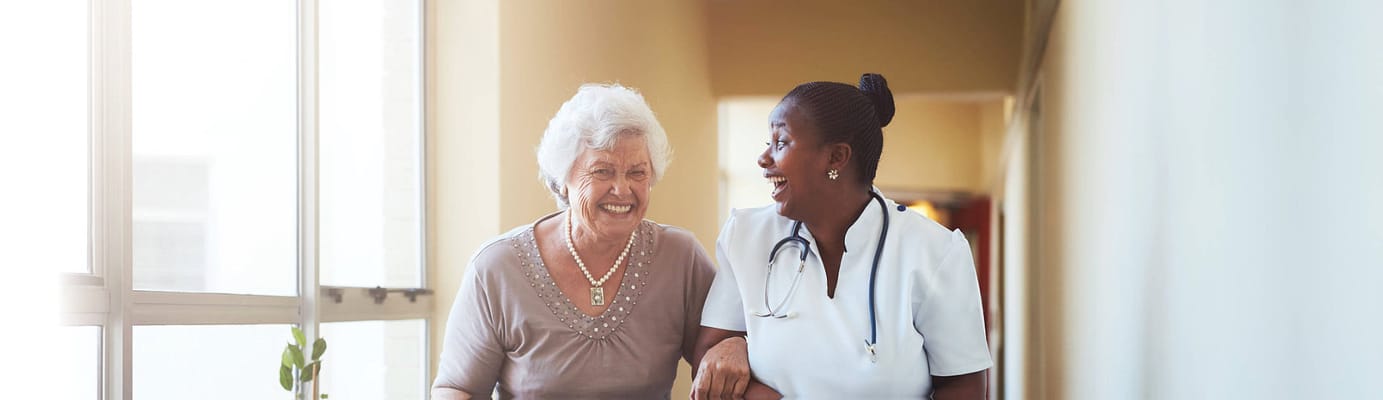 A caregiver and resident laughing in a hallway