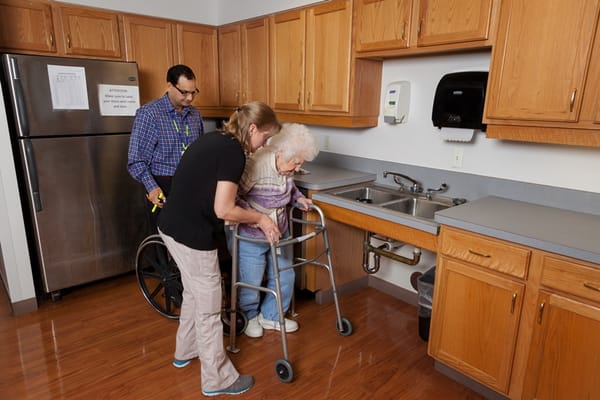 Staff assisting a senior in a kitchen area