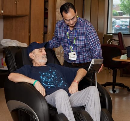 A caregiver assisting a resident in a recliner chair