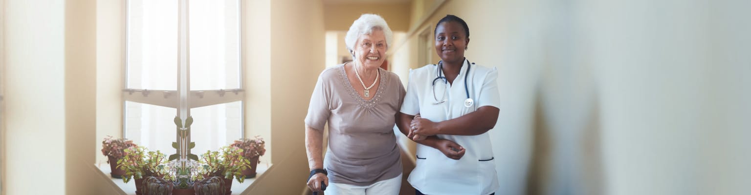 A resident walking with a caregiver in a hallway