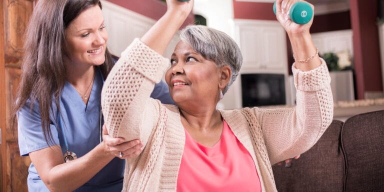 A caregiver assisting a resident with light weights