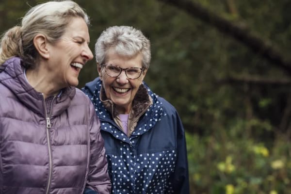 Two senior women laughing outdoors in nature