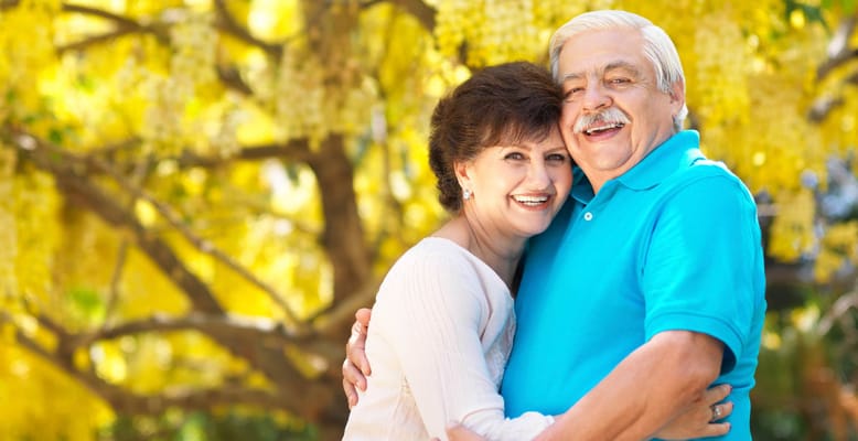Couple posing together in front of yellow flowers