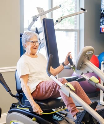 Resident exercising on a fitness machine in a bright room