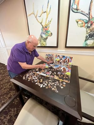 Resident assembling a jigsaw puzzle in an activity room