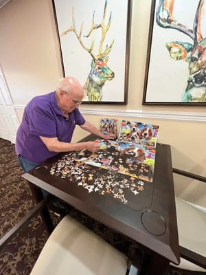 Resident assembling a jigsaw puzzle in an activity room