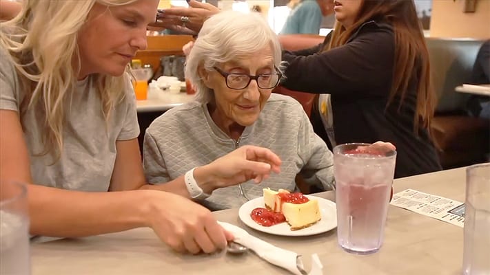 Resident enjoying dessert with family in a dining area