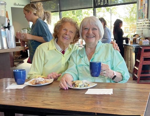 Two residents enjoying coffee and pastries in a dining area
