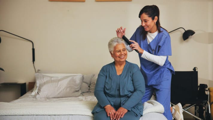 Care staff styling hair for a resident in a cozy room