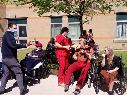 Residents enjoying a sunny day outside with staff assistance