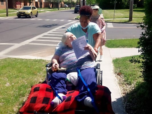 A caregiver assisting a resident in a wheelchair outdoors