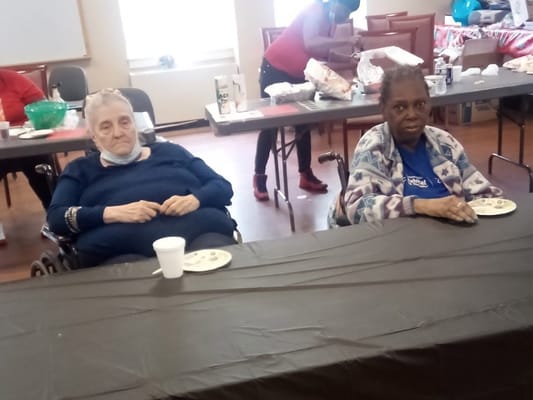 Two residents enjoying snacks at a table