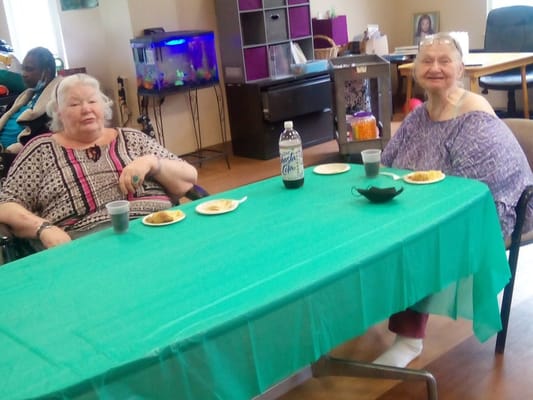 Two residents enjoying snacks at a table