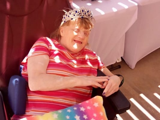 Resident wearing a crown, smiling in a colorful outfit