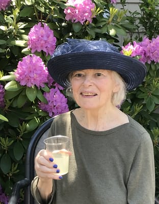 A woman enjoying a drink in a garden with flowers