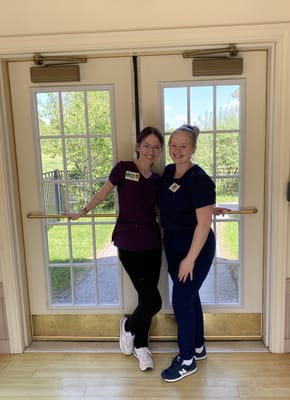 Staff members smiling by the entrance doors with a view of greenery