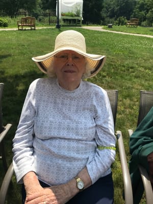 Elderly resident sitting outdoors in a sunny garden