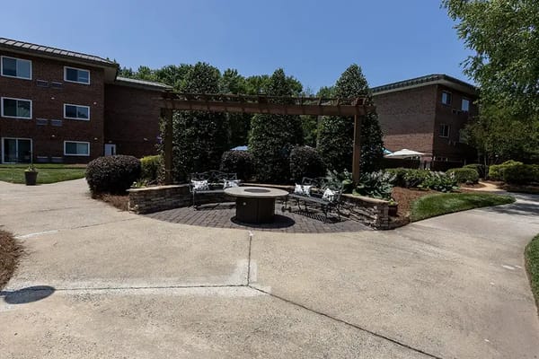 Outdoor seating area with a fire pit surrounded by greenery
