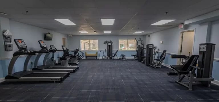 Empty fitness room with exercise equipment and light blue walls