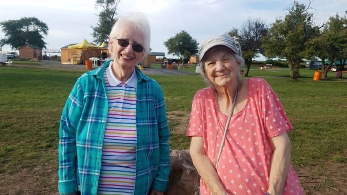 Two smiling residents in a grassy outdoor area