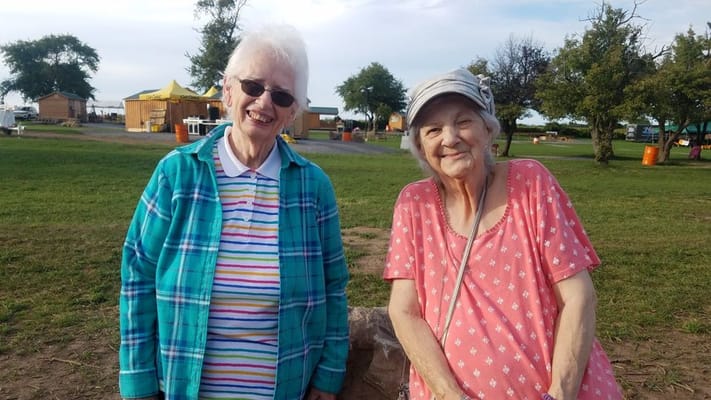 Two smiling residents in a grassy outdoor area