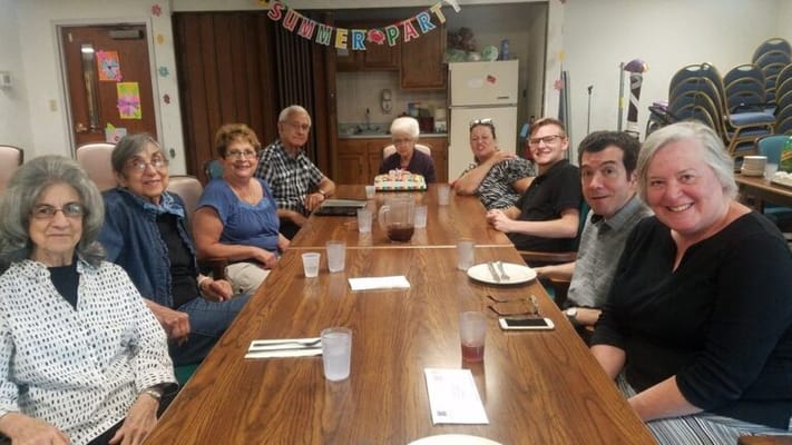 Residents and staff gathered at a dining table for a summer party