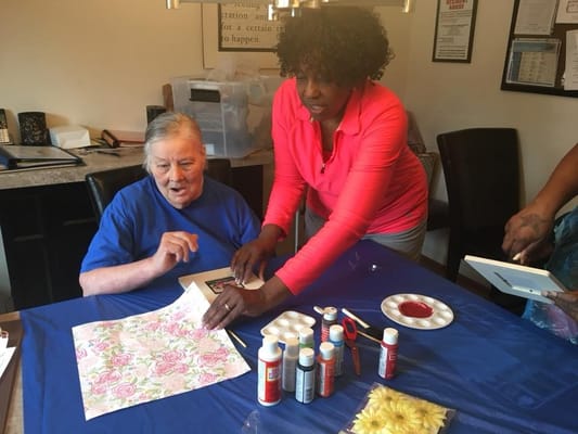Resident engaging in an art activity with staff assistance