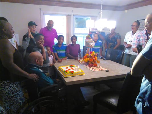 Residents celebrating a birthday with a cake in an activity room