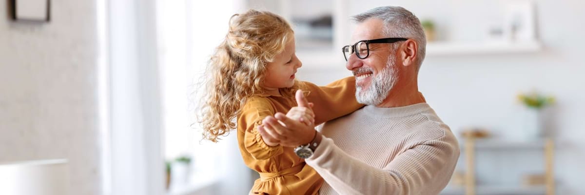 A man playing with a young girl indoors
