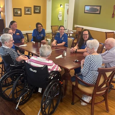Residents and staff engaged in conversation at a dining table
