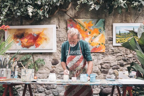 An artist painting in a garden with vibrant artwork