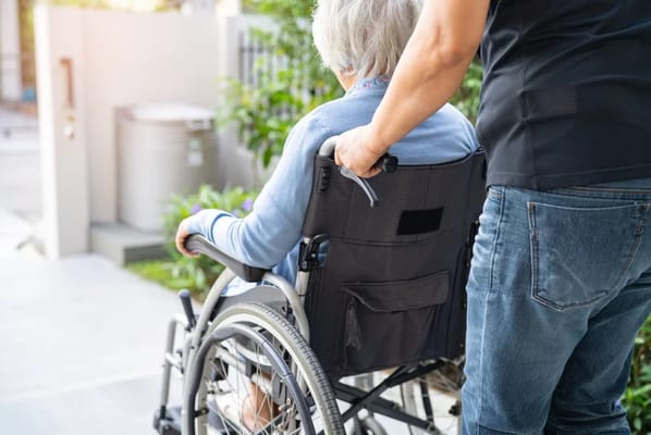 Caregiver assisting a senior in a wheelchair outdoors