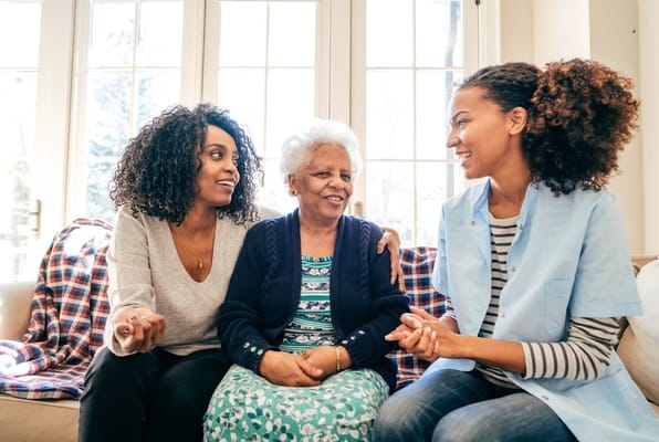 Two caregivers and a senior resident chatting in a cozy setting