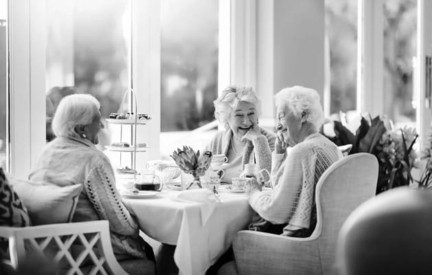 Three senior women enjoying tea and conversation at a table