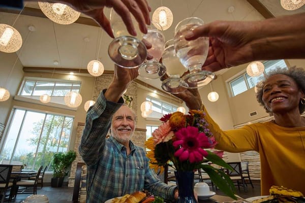 Residents toasting with drinks at a dining table