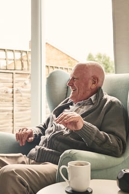 Senior man smiling in a cozy chair indoors