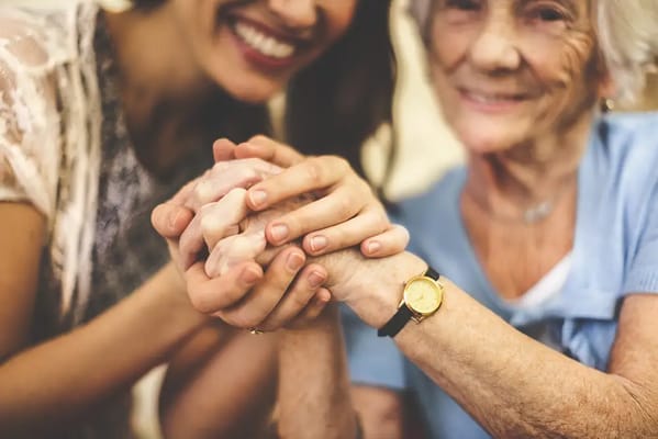 Close-up of a caregiver holding hands with a senior resident