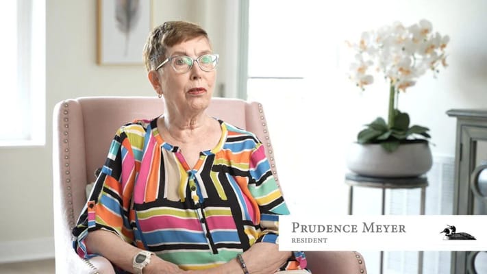 A resident seated in a colorful blouse in a well-lit room