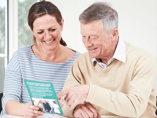Senior resident and staff member sharing a moment over a brochure