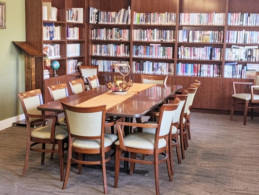 A cozy common area with bookshelves and dining table
