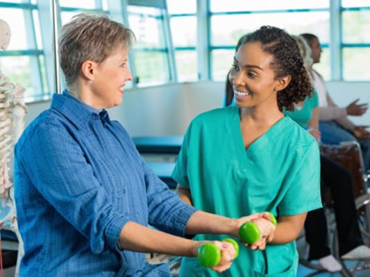 A therapist assisting a resident with weights in a therapy room
