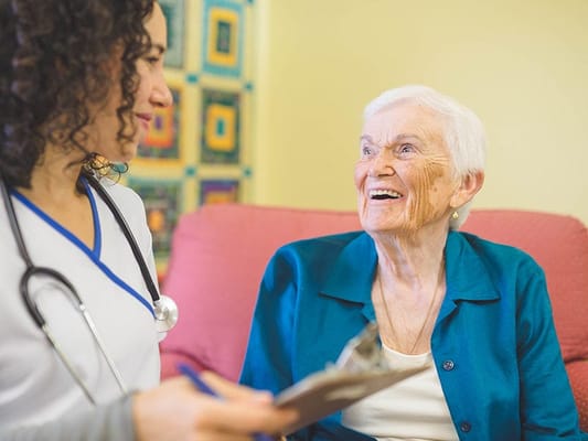 A healthcare worker interacting with a smiling resident